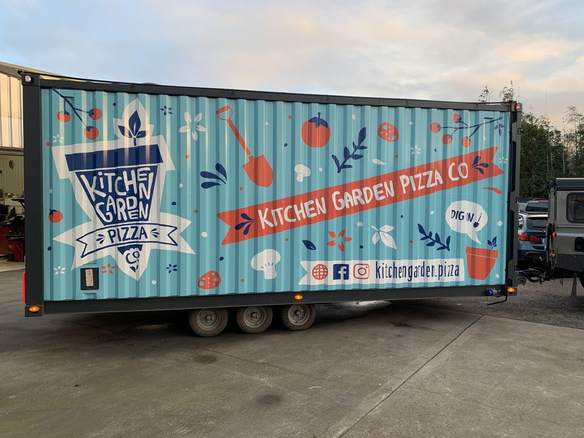 A kitchen garden pizza truck is parked in a parking lot.
