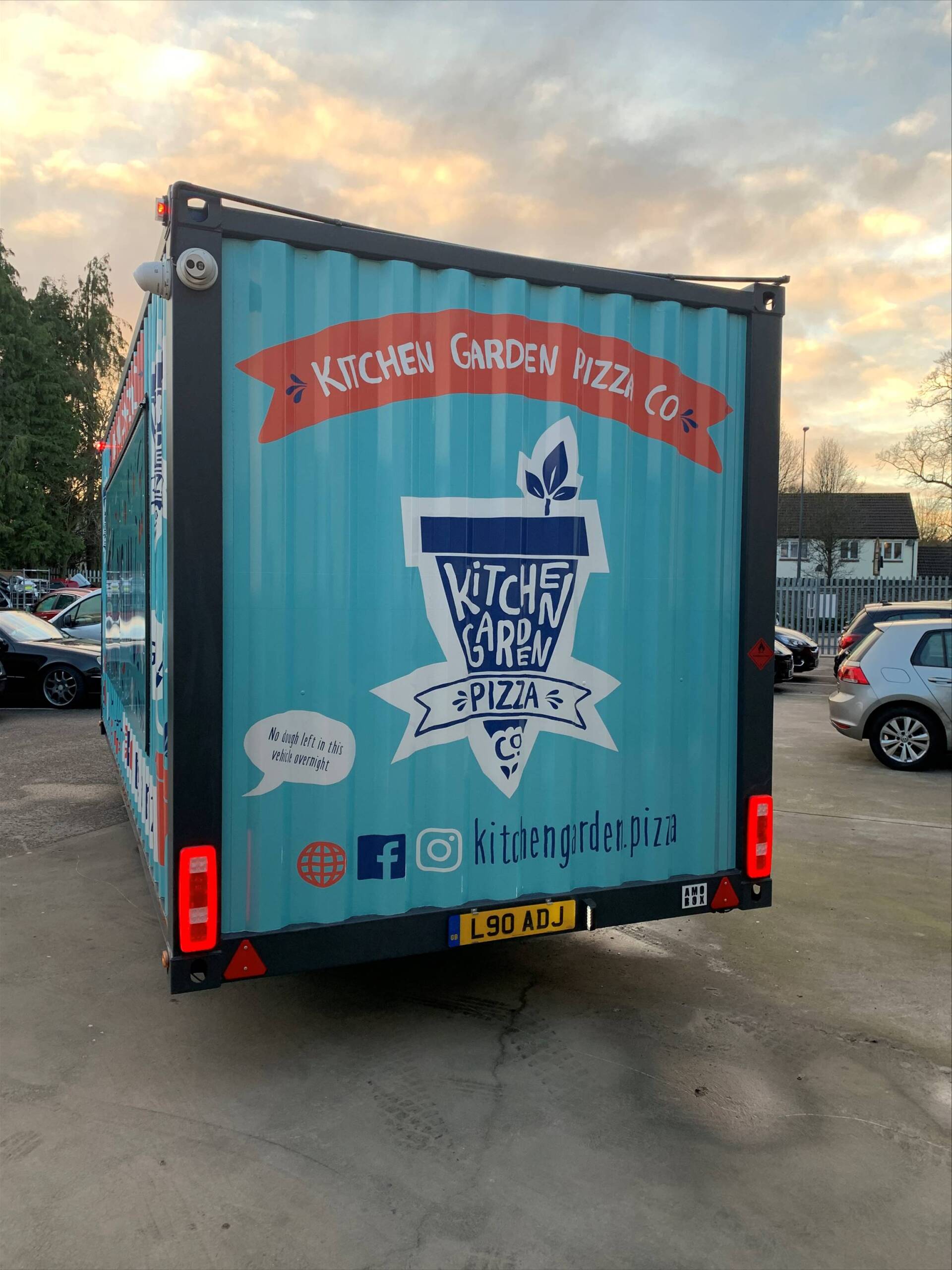 A blue truck with a witch brew logo on the back is parked in a parking lot.