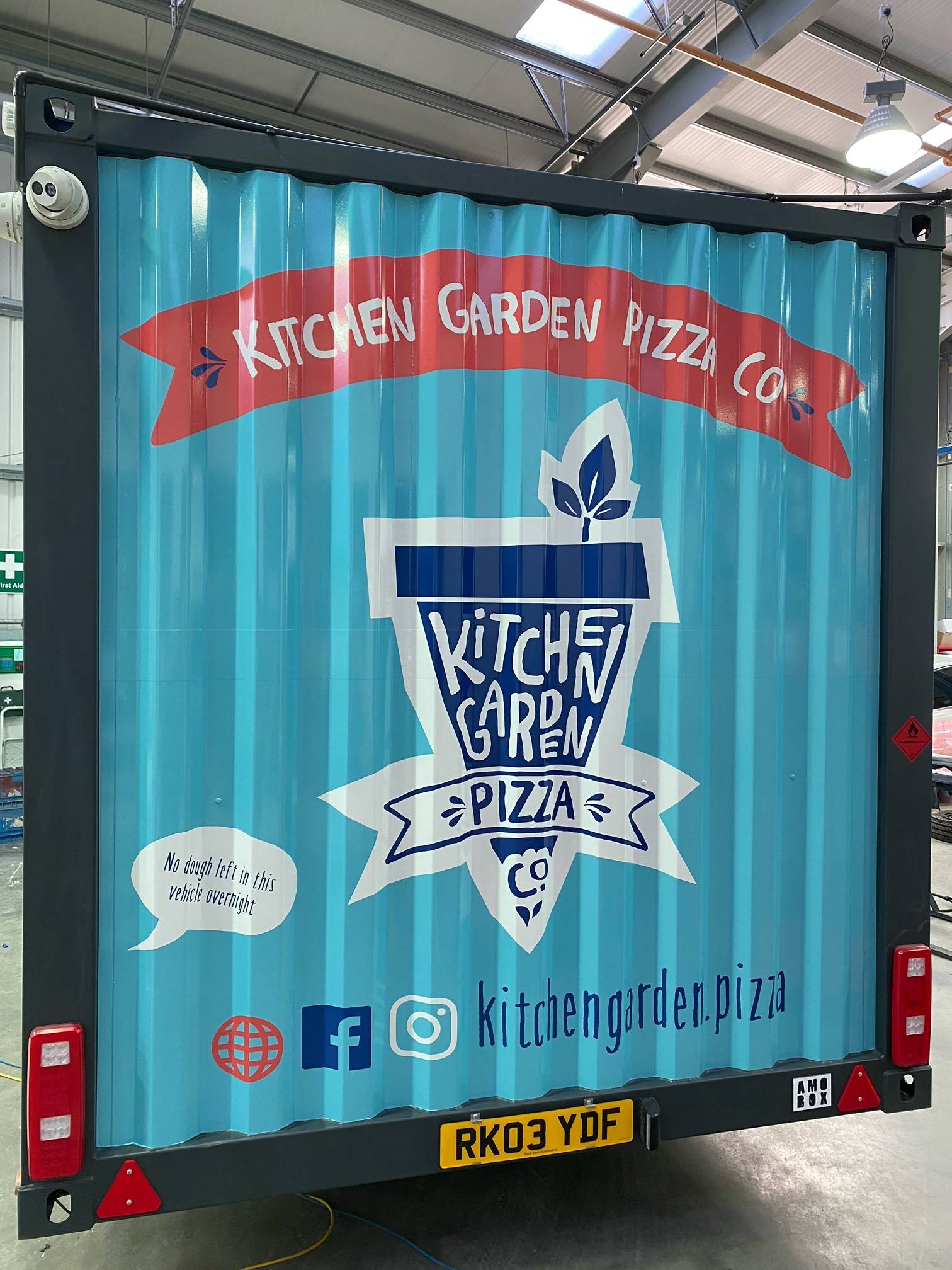 A kitchen garden pizza truck is parked in a garage.