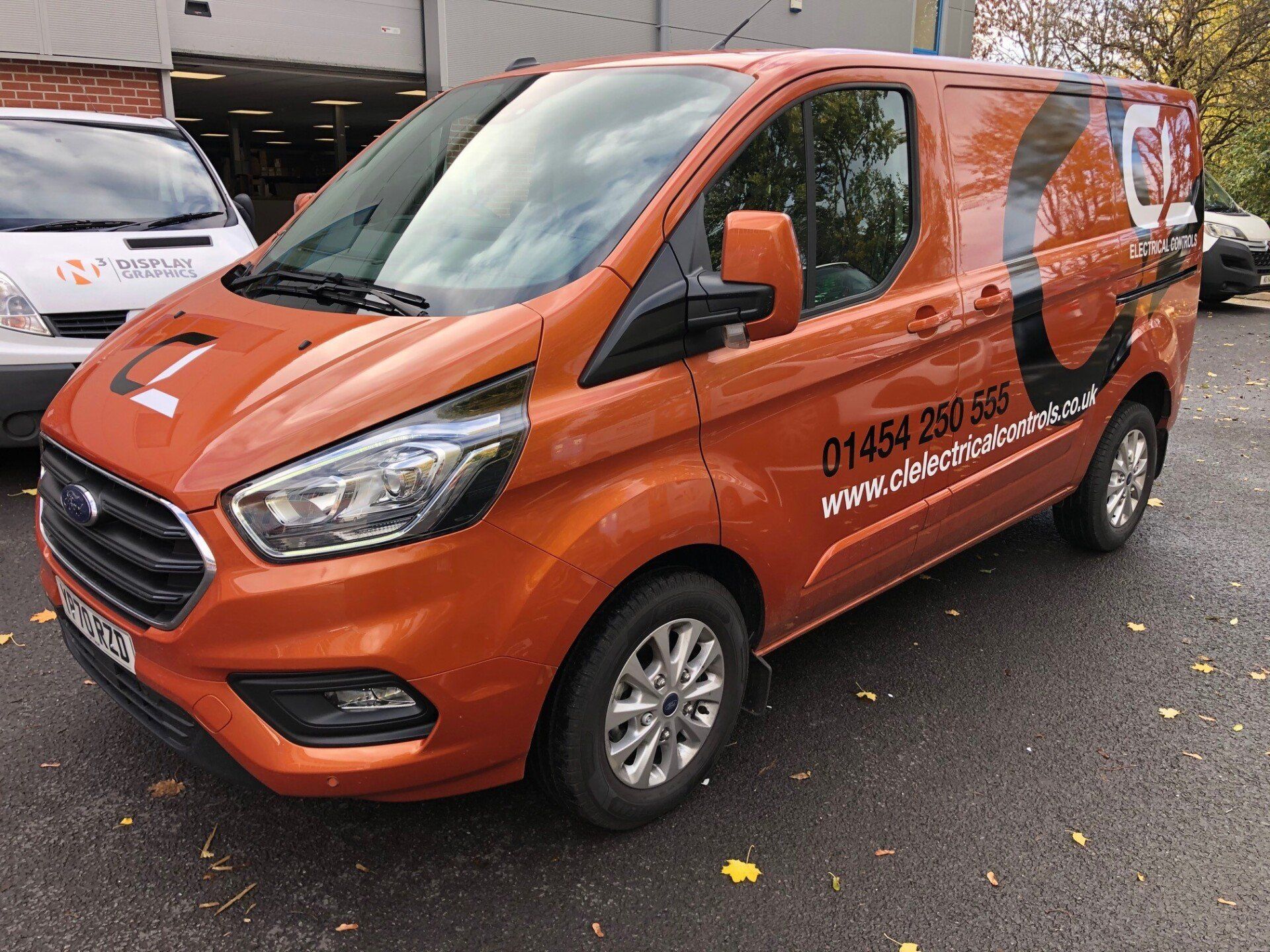 An orange van is parked in a parking lot.