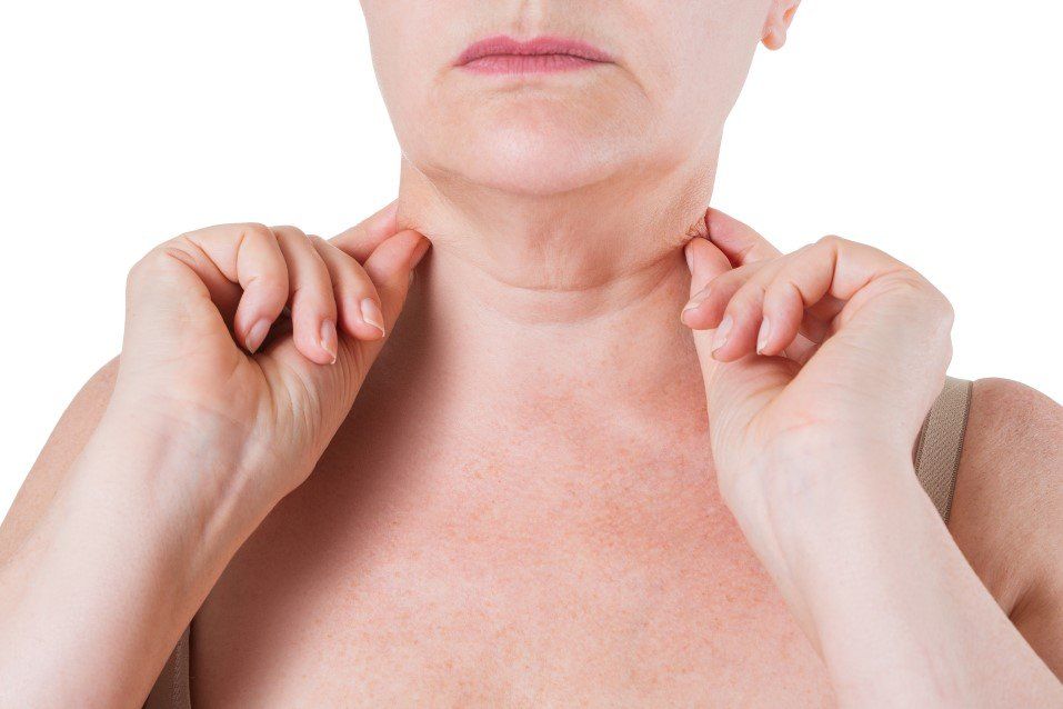 Person touching the sides of their neck and upper chest, showing redness and irritation.