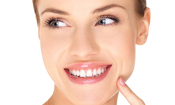 Close-up of a smiling woman pointing to her teeth on a white background
