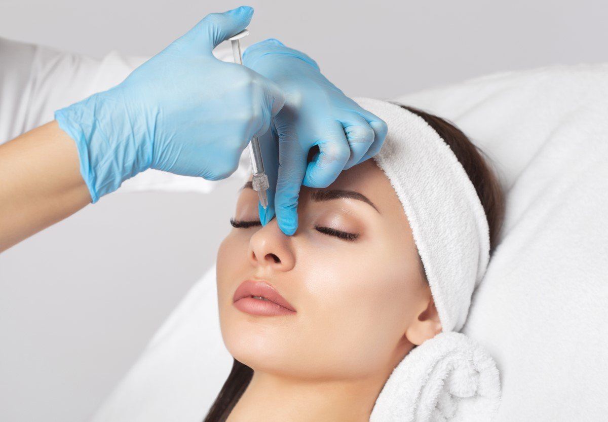 Gloved hands apply treatment to a woman’s nose in a spa setting