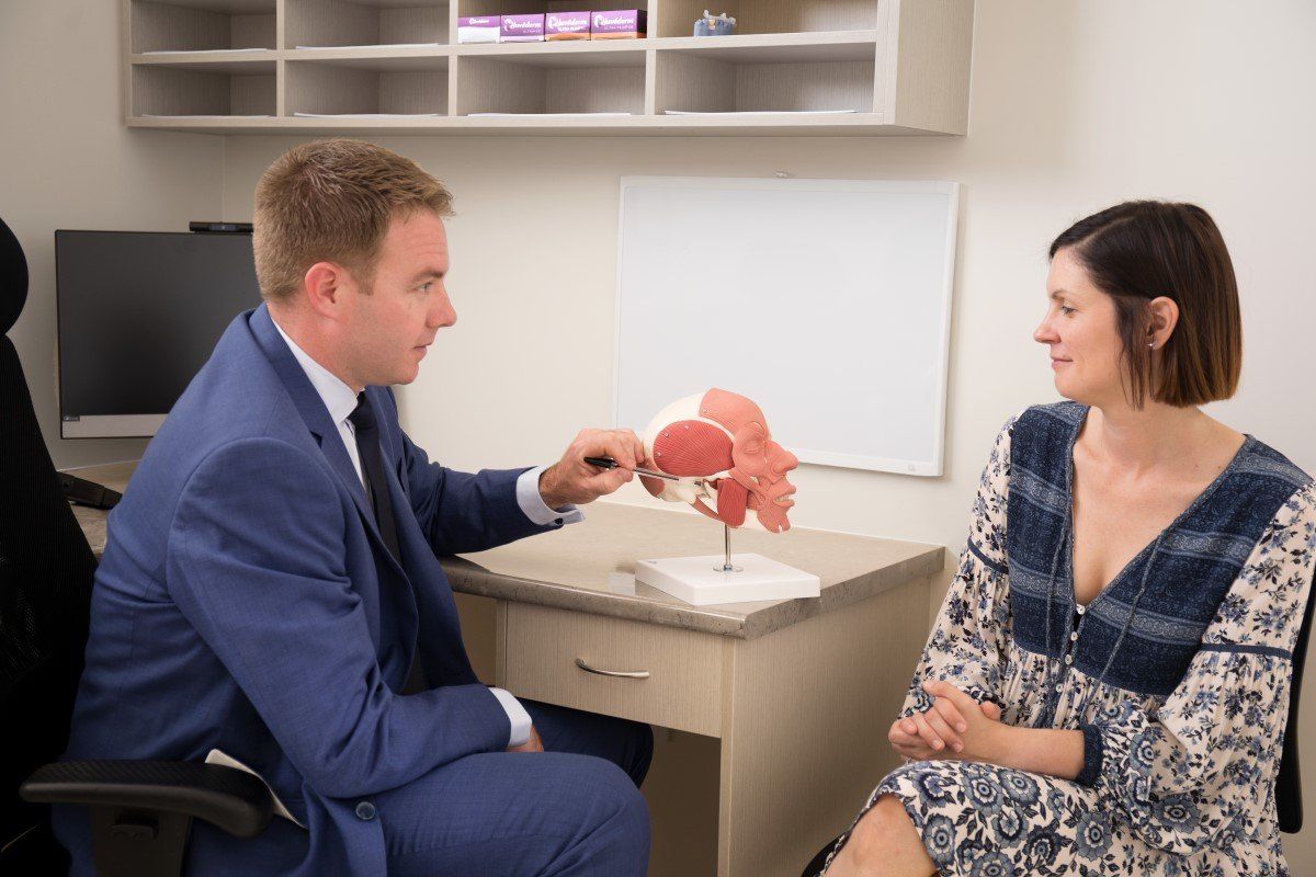Doctor showing a pelvic model to a seated patient in a clinic exam room