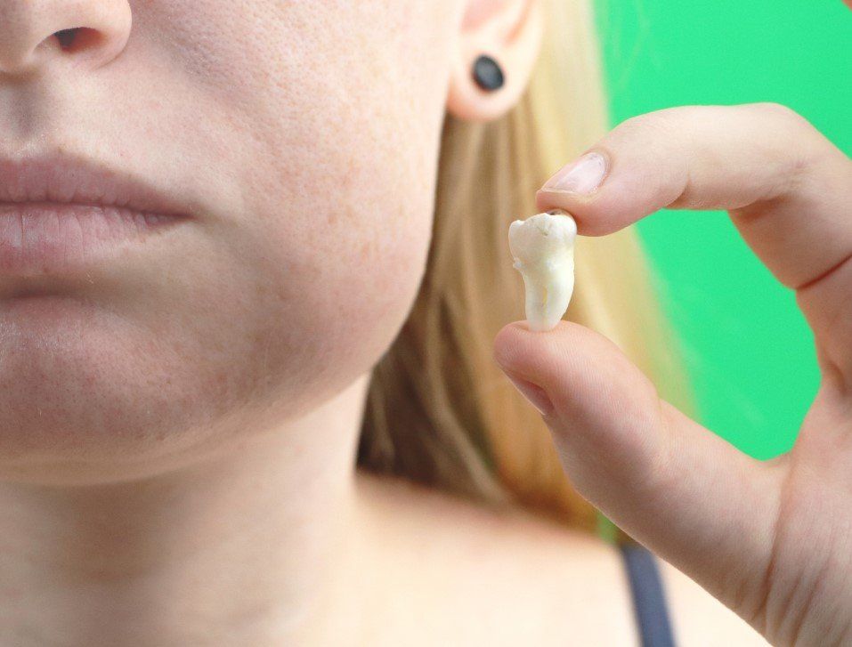 Person holding a small white dental mold near their mouth, close-up on face and hand