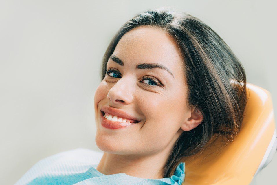 Smiling woman reclining in an orange chair, looking at the camera.