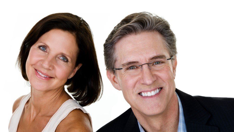 Two smiling professionals, a woman and man, posed against a white background