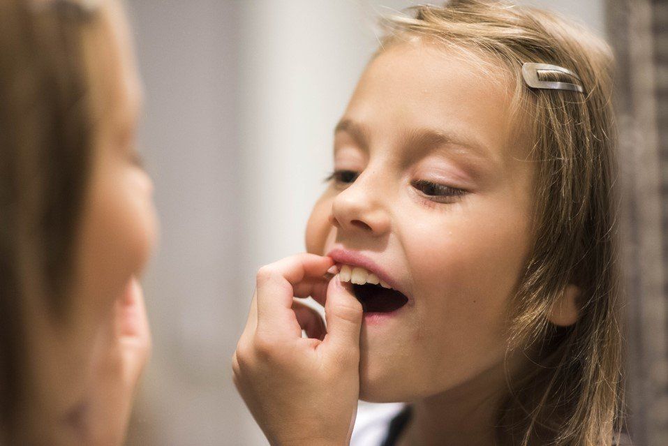 Girl applying lip balm while looking in a mirror