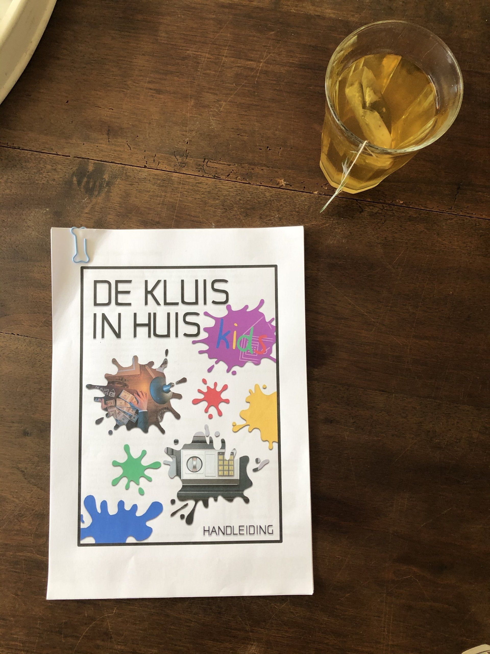 Op een tafel ligt naast een glas thee een boek met de titel De kluis in huis