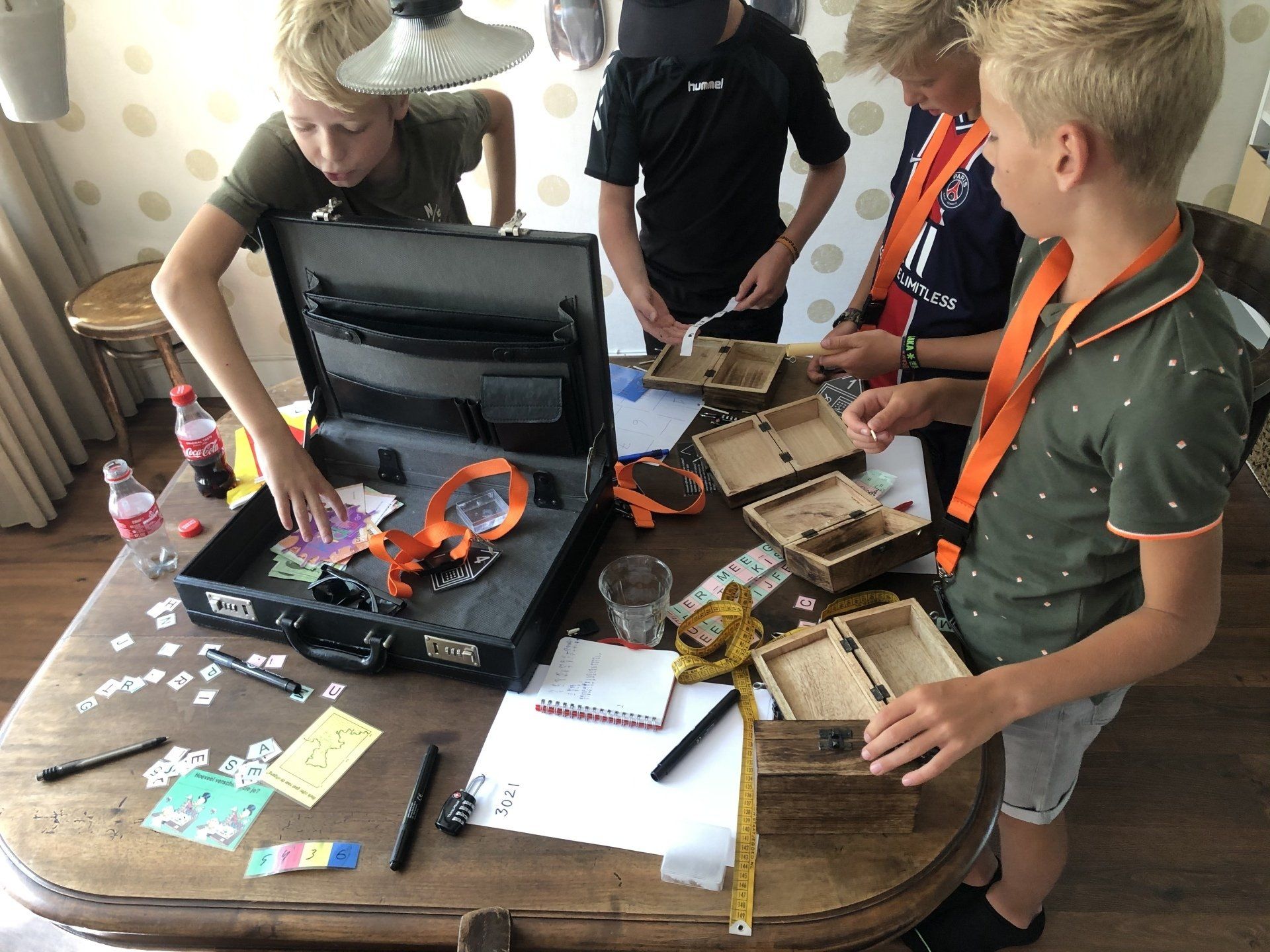 Een groep jonge jongens speelt een spel met een koffertje op een tafel.