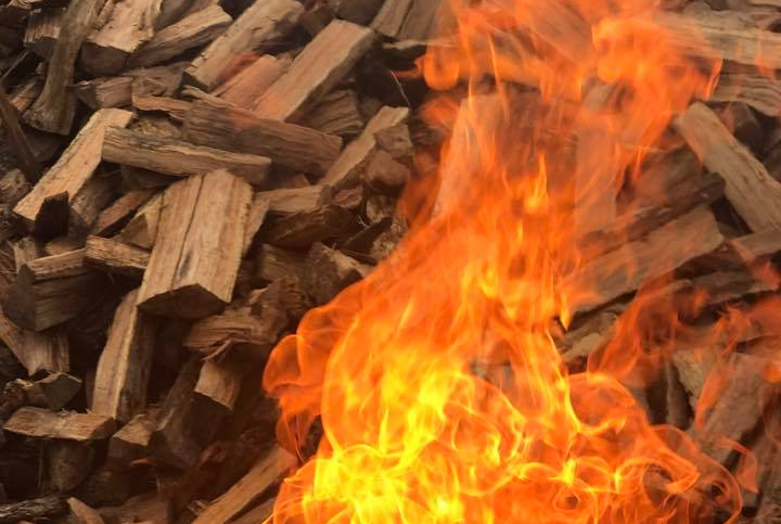 Flames engulfing a pile of split firewood, showcasing oranges, reds, and yellows.