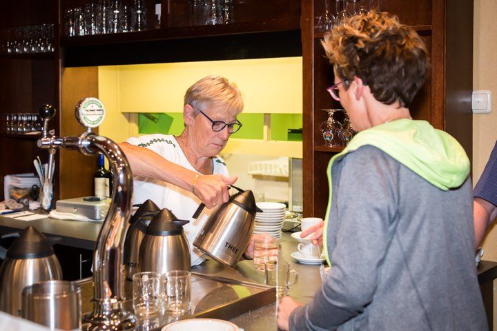 Een vrouw schenkt koffie in voor een klant aan de bar.