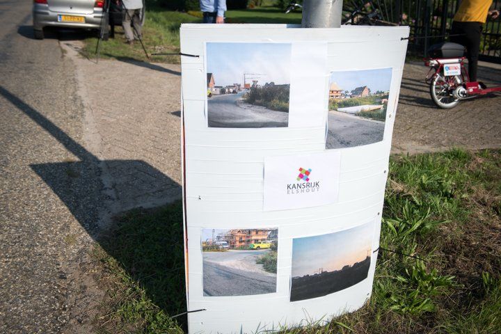 Wegwijzer met foto's ernaast, langs de weg.