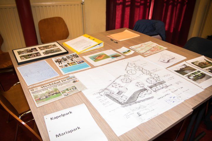 Een tafel met ontwerptekeningen, foto's en documenten, met het opschrift 