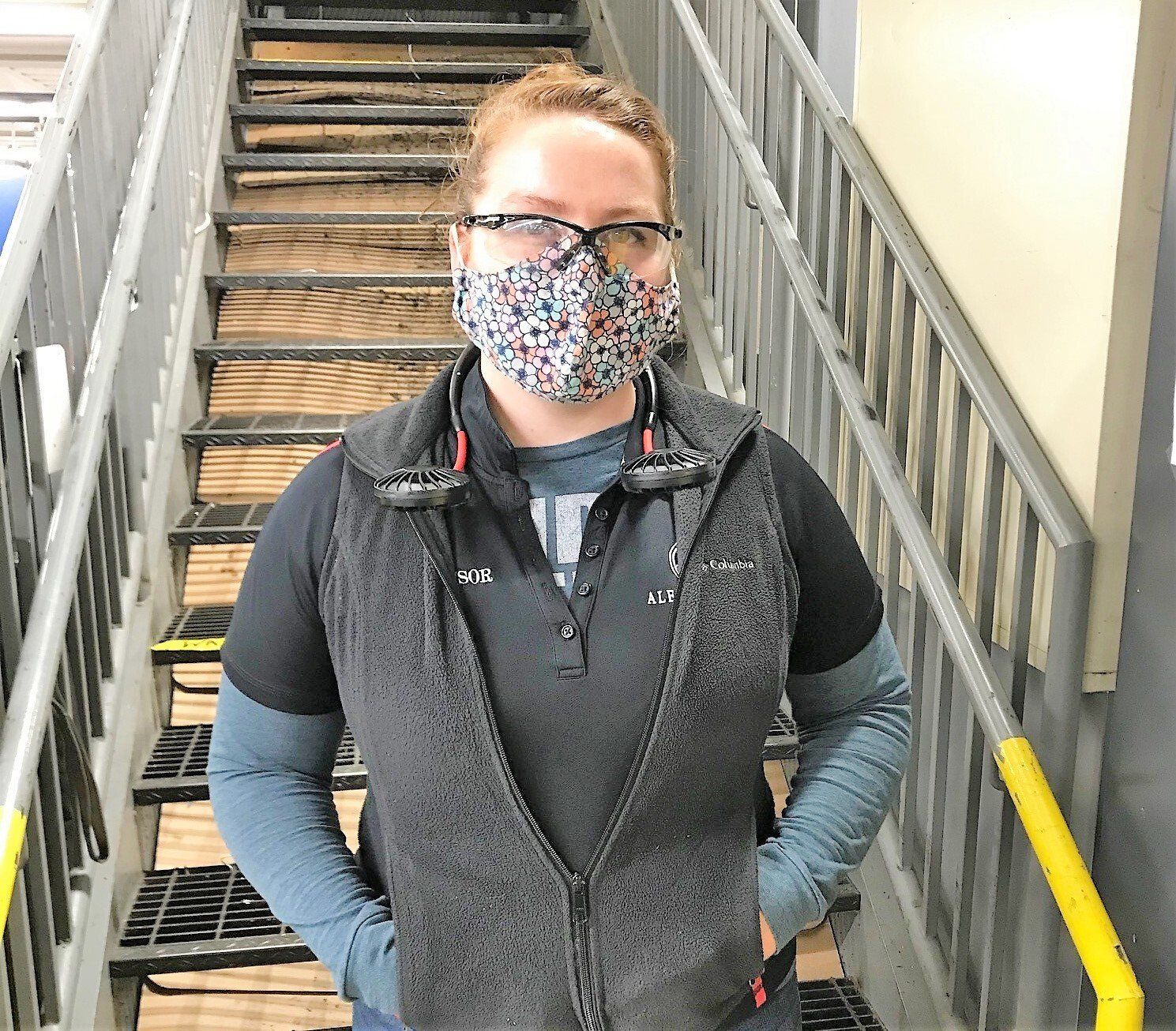 A woman wearing a mask and glasses is standing on a set of stairs.