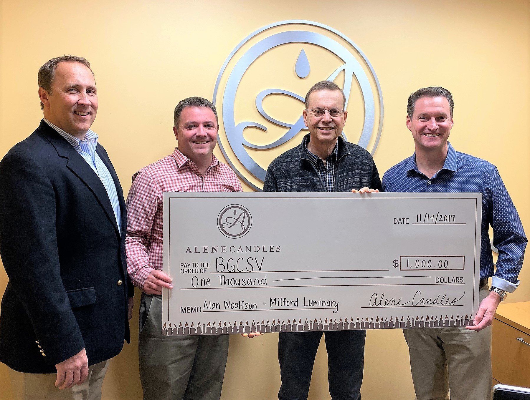 A group of men are standing next to each other holding a large check.