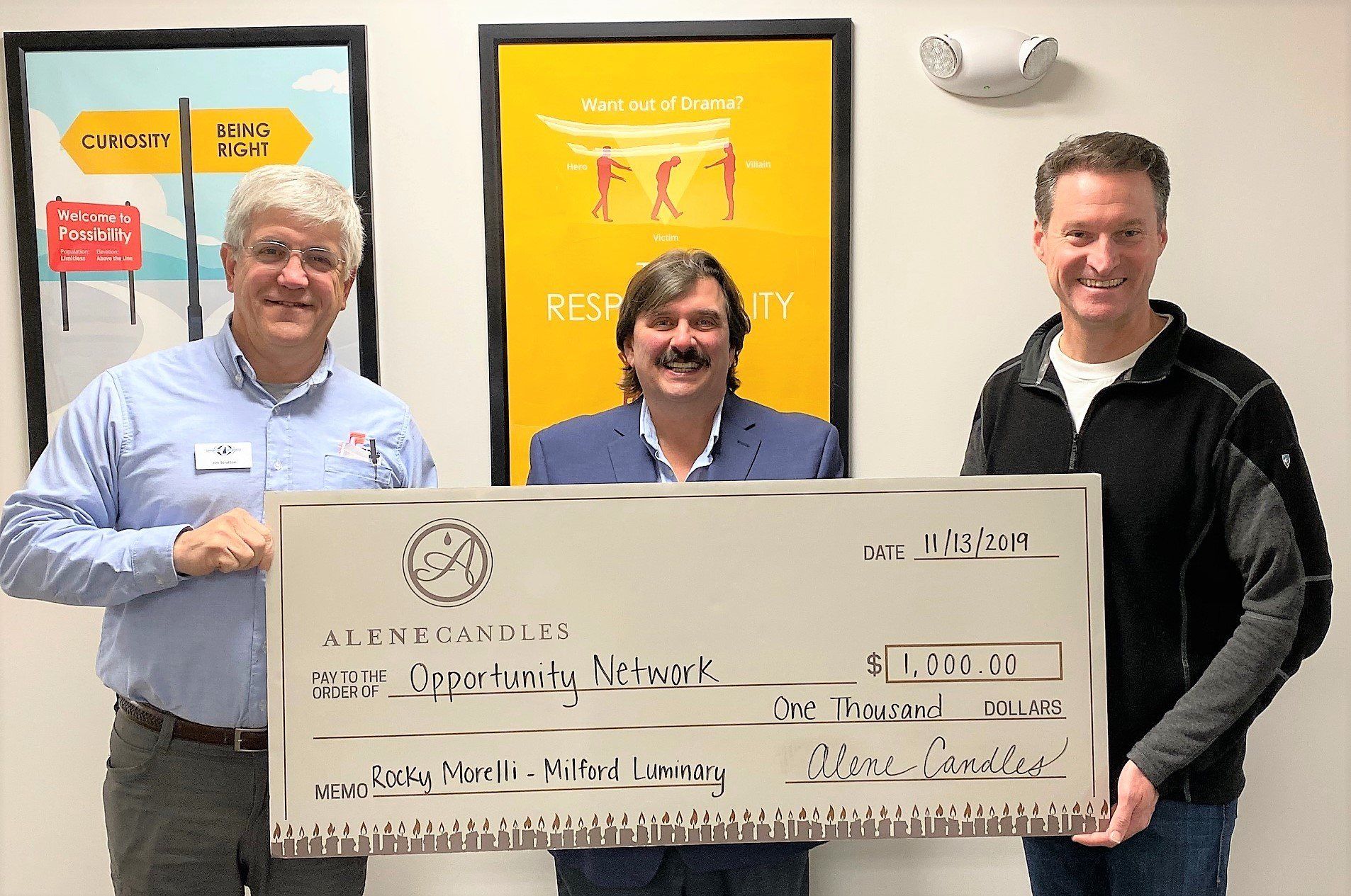 Three men are holding a large check in their hands