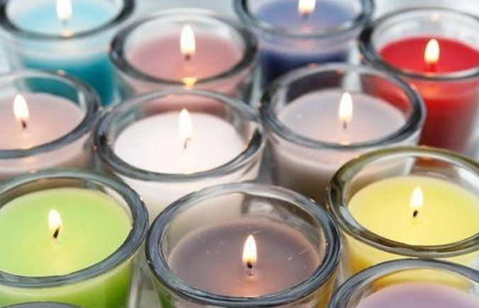 A bunch of different colored candles in clear glasses
