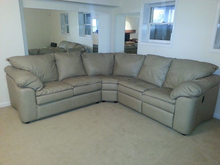 Tan leather sectional sofa in a room with neutral walls and carpet.
