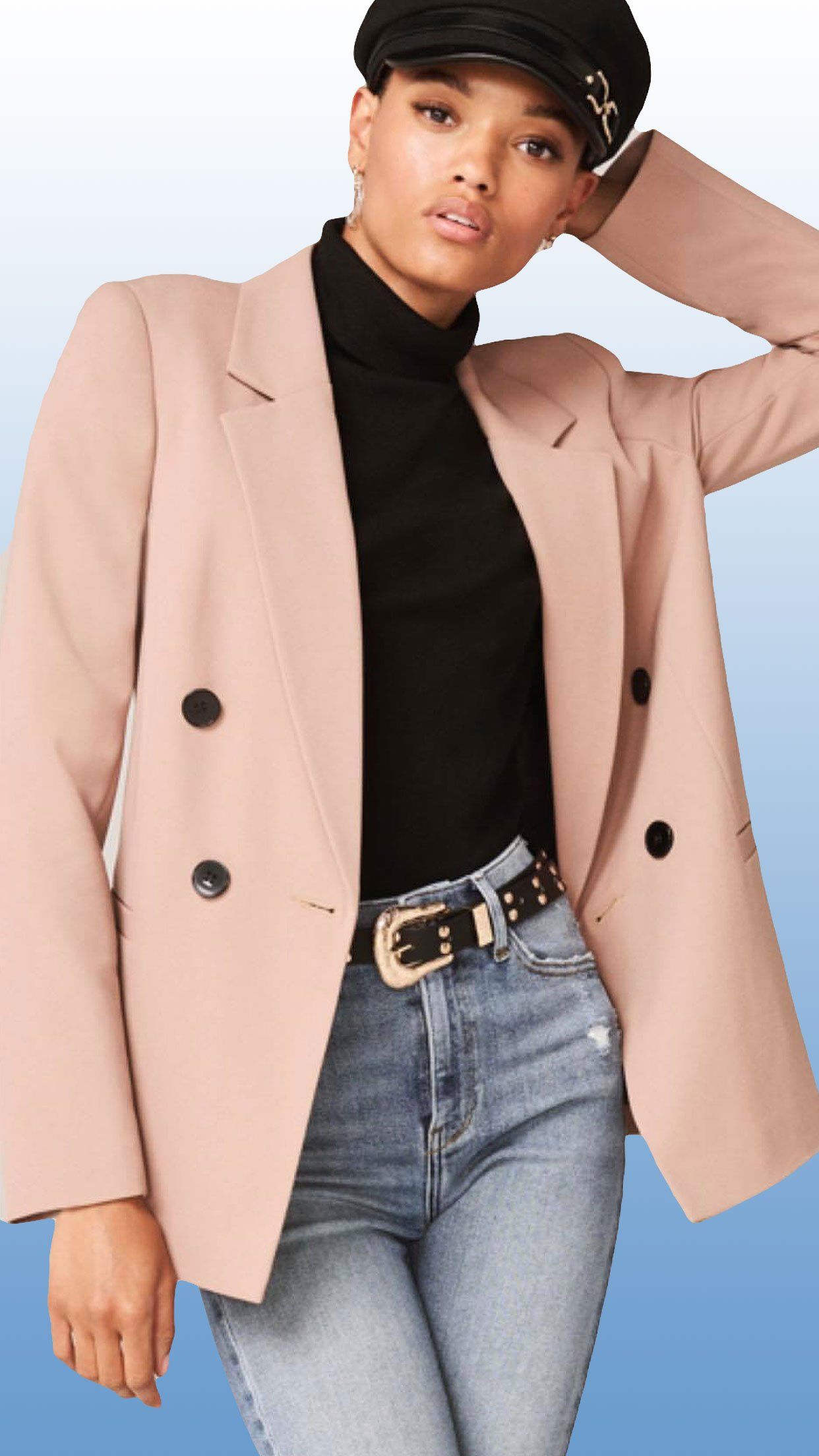 Woman wearing a pink blazer, black turtleneck, and jeans with a black belt, posing.