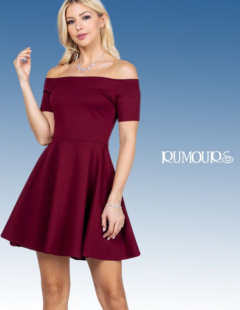 Woman in a burgundy off-the-shoulder dress, posing in front of a blue background.