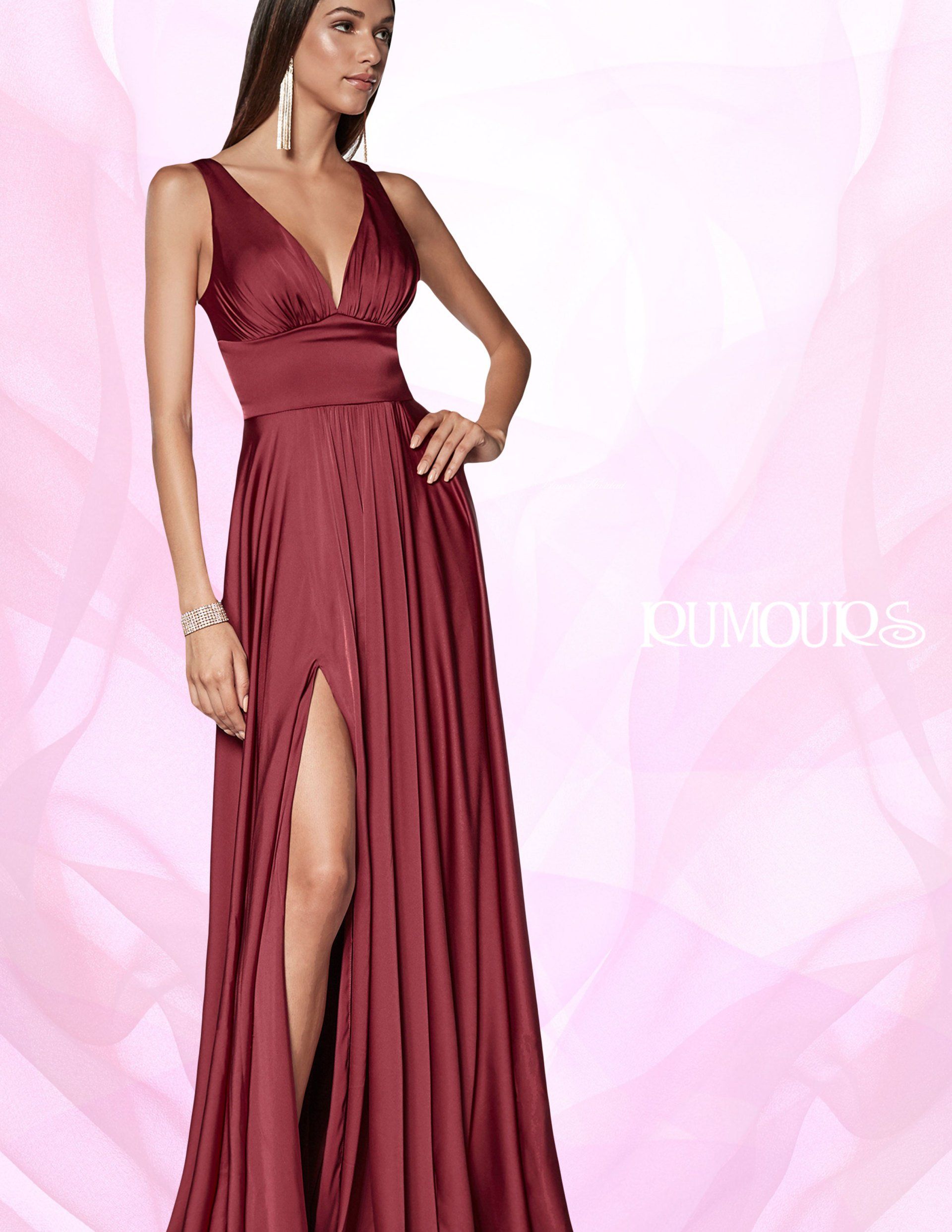 Woman in a burgundy formal gown with a high slit, posing with a hand on hip.