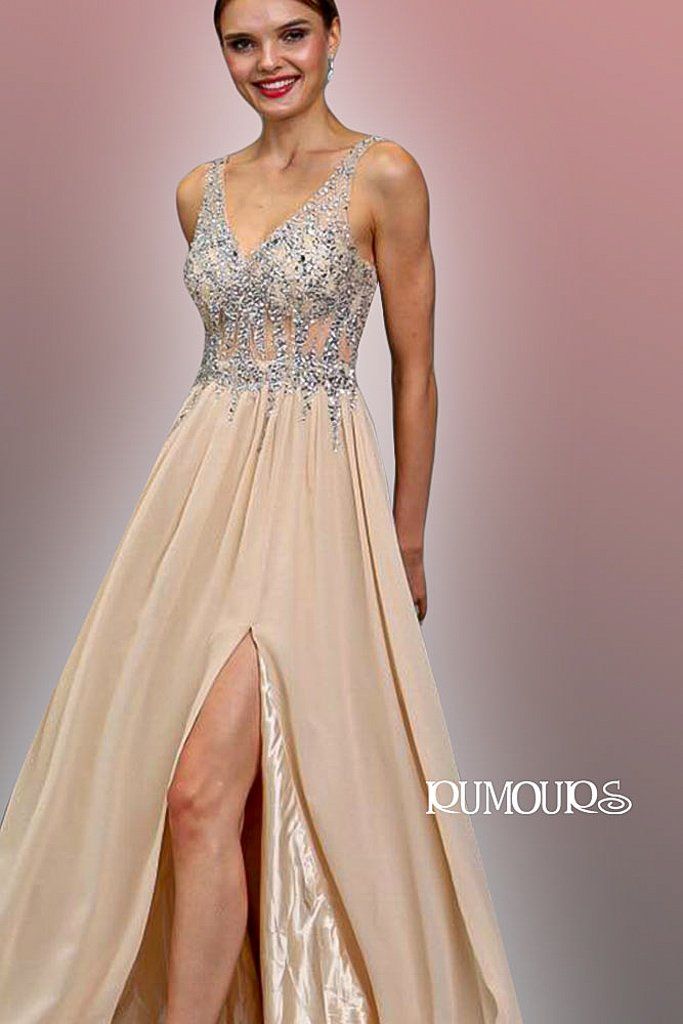 Woman in a beige formal dress with embellished bodice and high slit, posing indoors.
