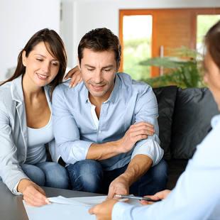 Couple reviewing financial books with a professional in a home setting.