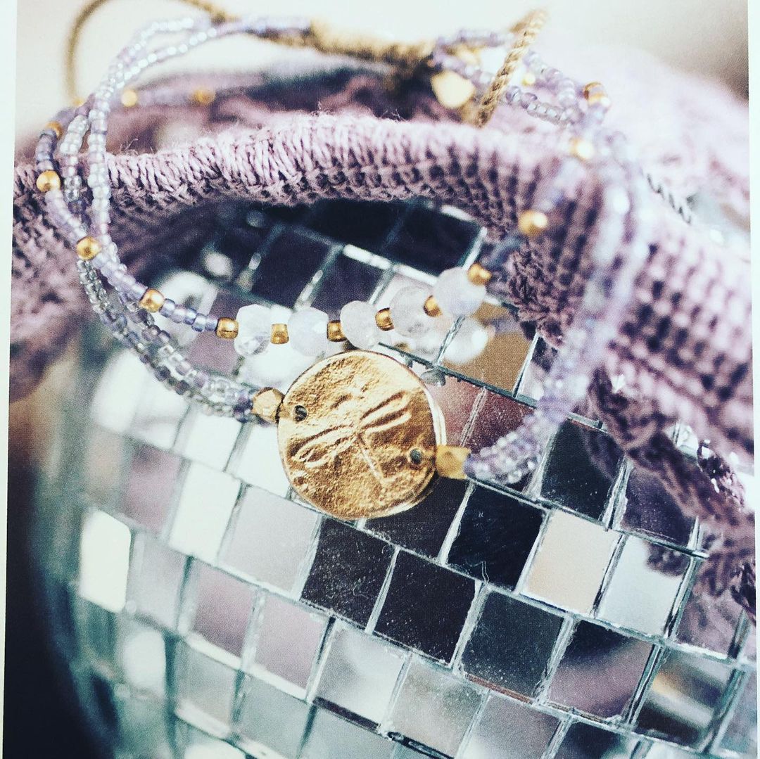 Primo piano di una borsa a mosaico argentata con nastro rosa e dettagli dorati.
