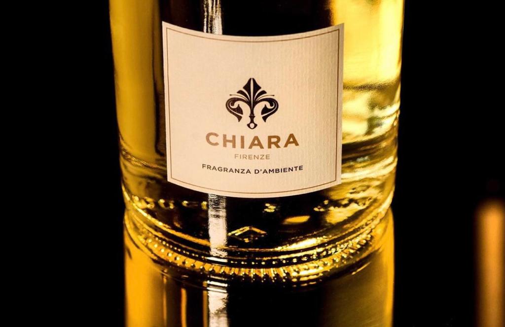 Primo piano dell'etichetta di una bottiglia di Chiara su un liquido dorato contro uno sfondo scuro.