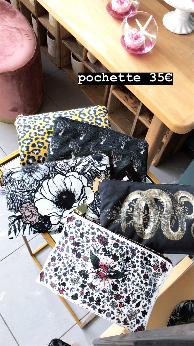 Borse con motivi floreali e a stampa pitonata in mostra in un negozio, etichettate “Pochette 35€”