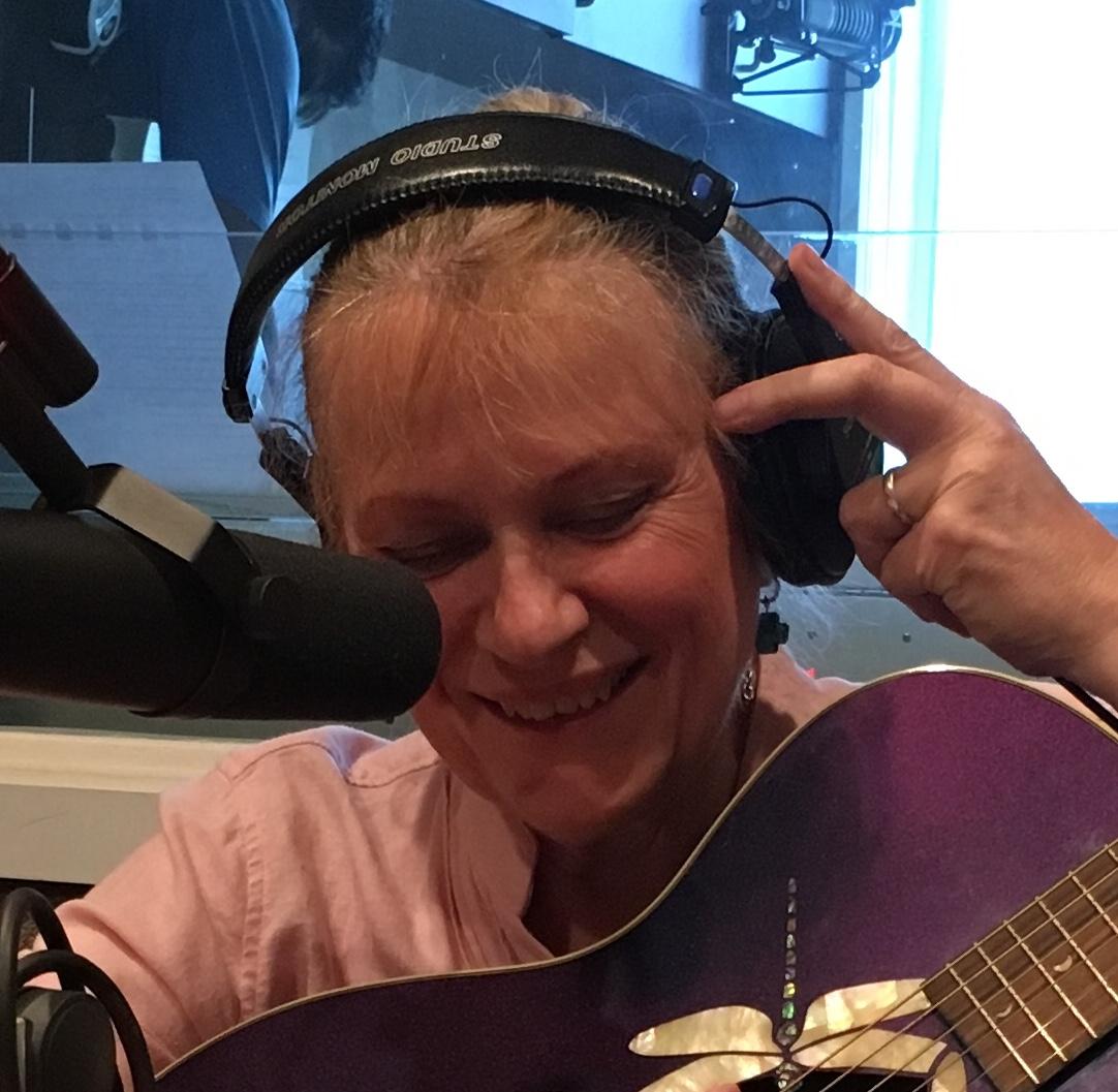 Lisa Dudley with microphone, earphones, Luna dragonfly guitar in recording studio