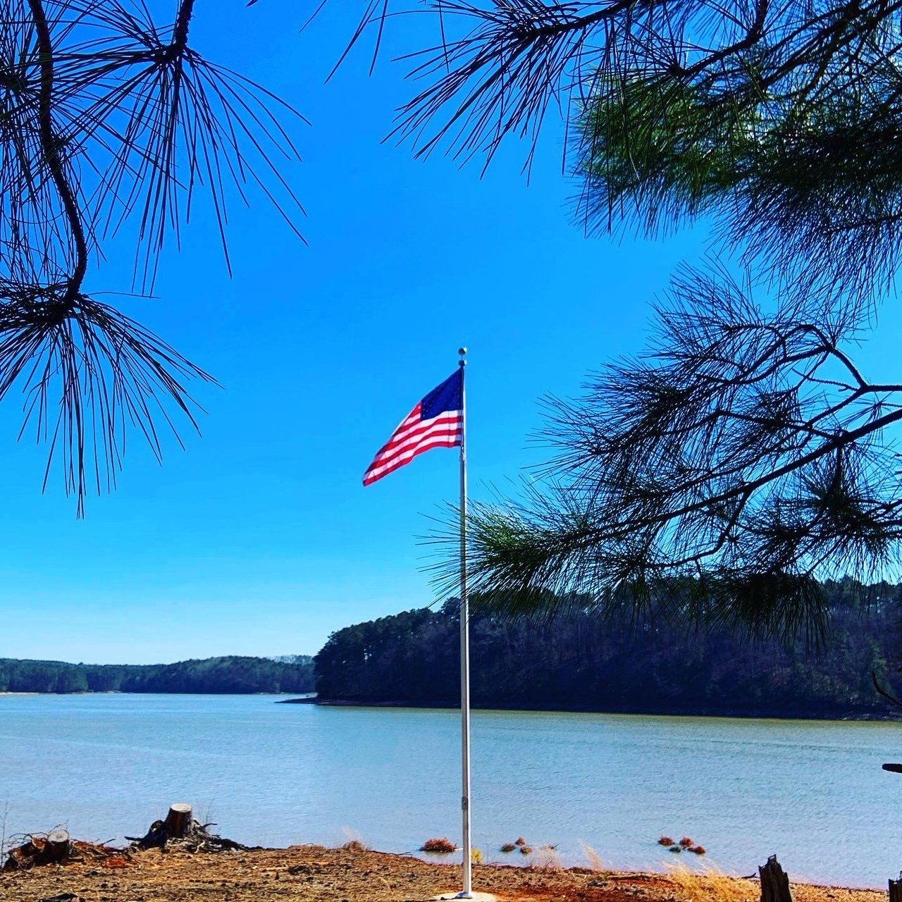 An american flag is flying in front of a body of water