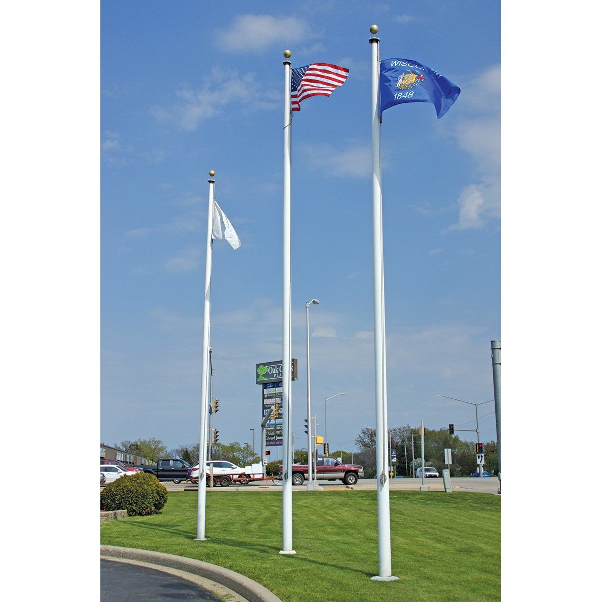 Three flags are on a pole in a grassy area