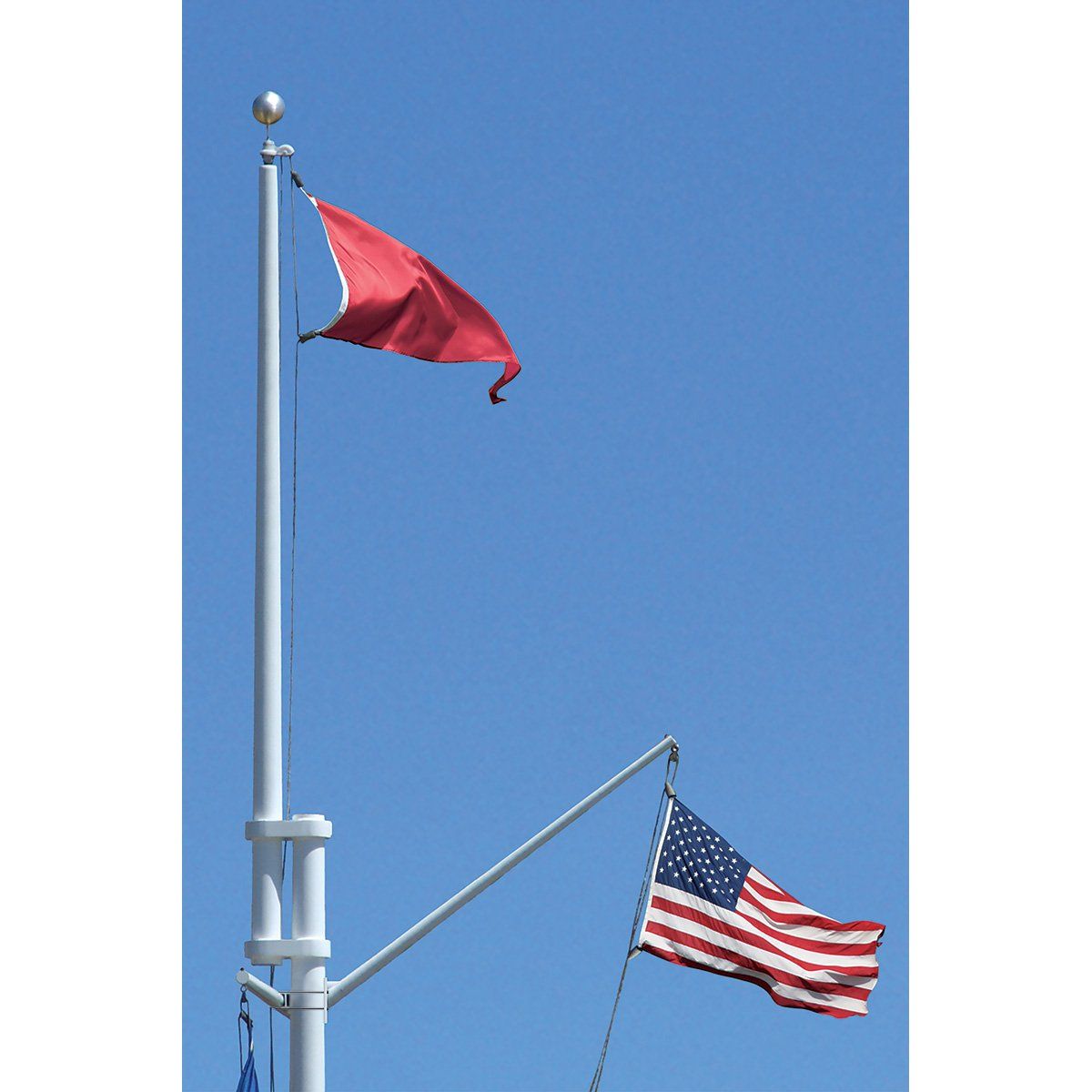 A red flag is flying next to an american flag