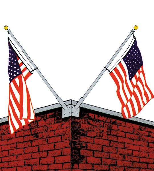 Two american flags are flying on top of a red brick building