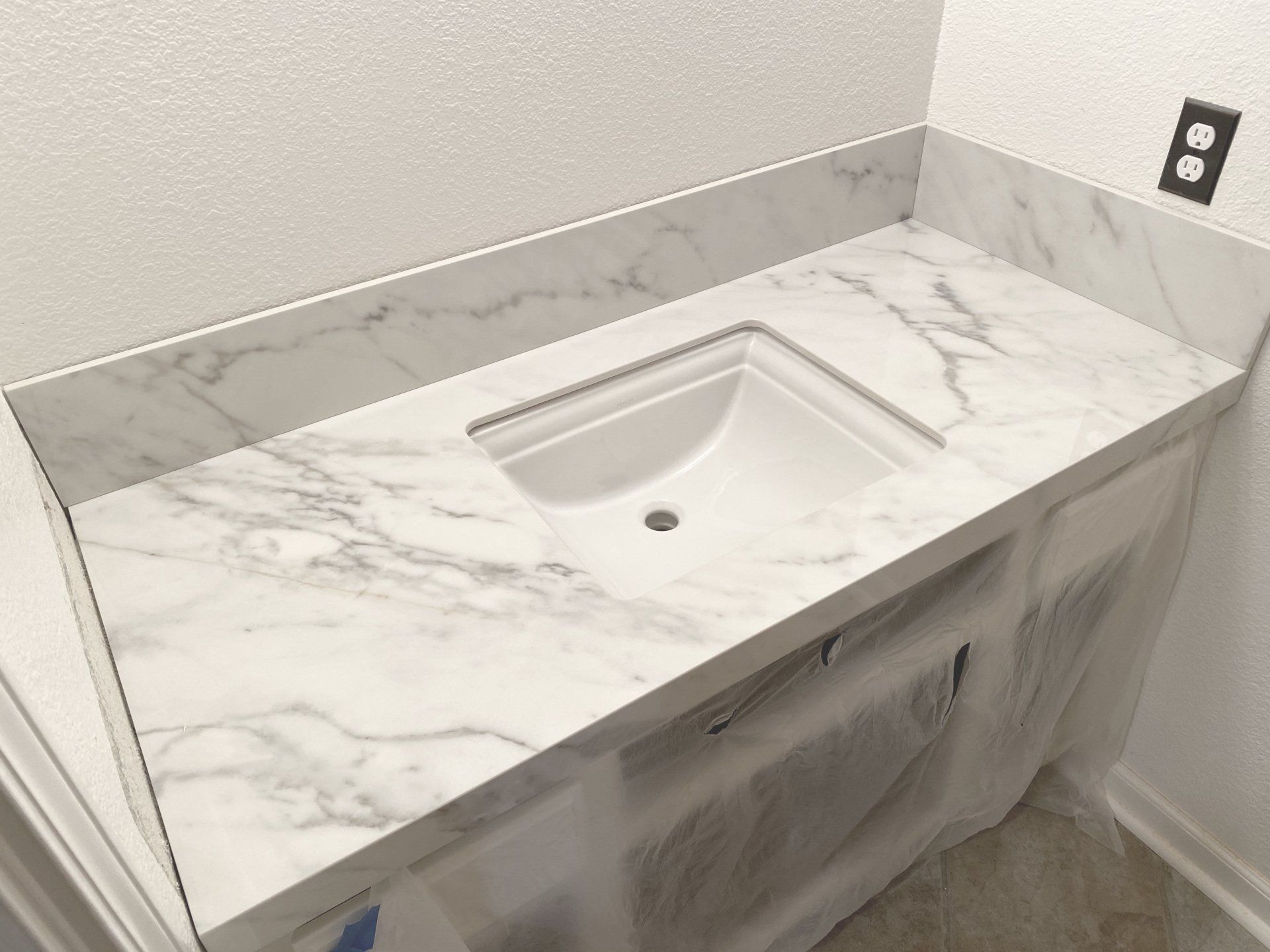 A bathroom vanity with a sink and a marble counter top.