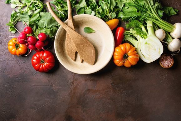 Verdure su tavolo con piatto in primo piano