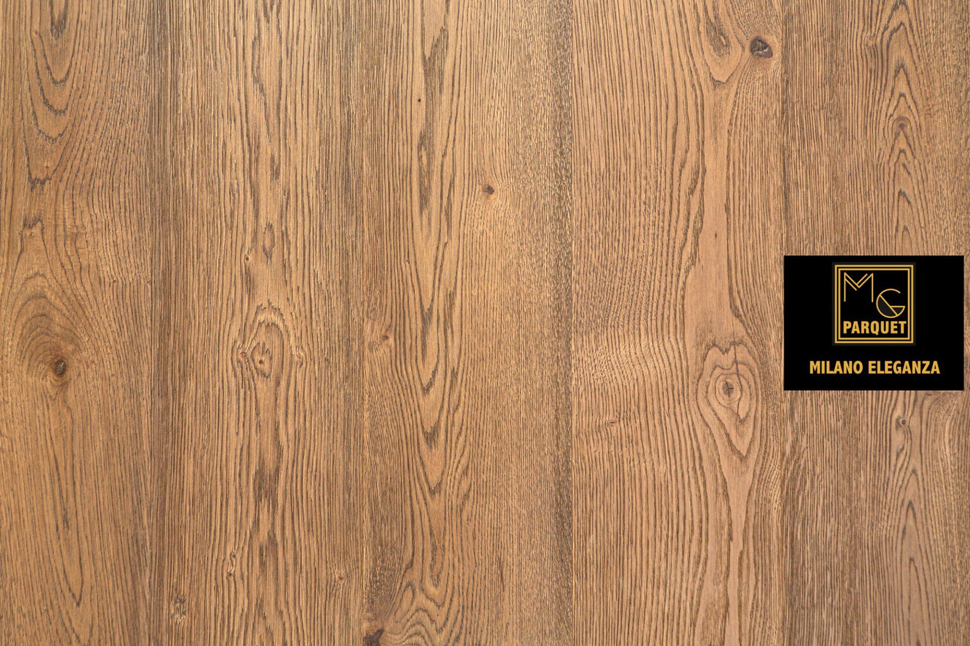 Pavimento in legno marrone chiaro con venature visibili, con logo nero e oro nell'angolo in basso a destra.