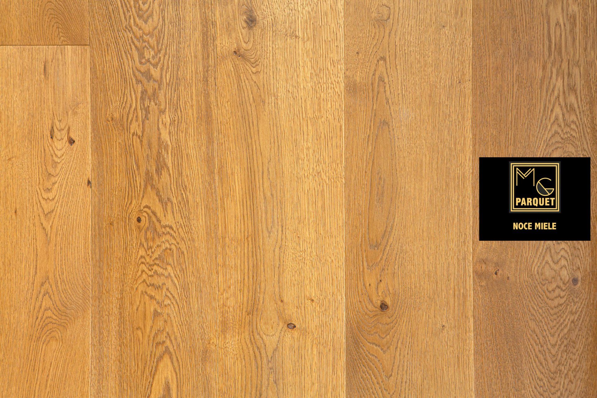 Pavimento in legno con finitura marrone-dorata e logo del produttore sul lato destro.