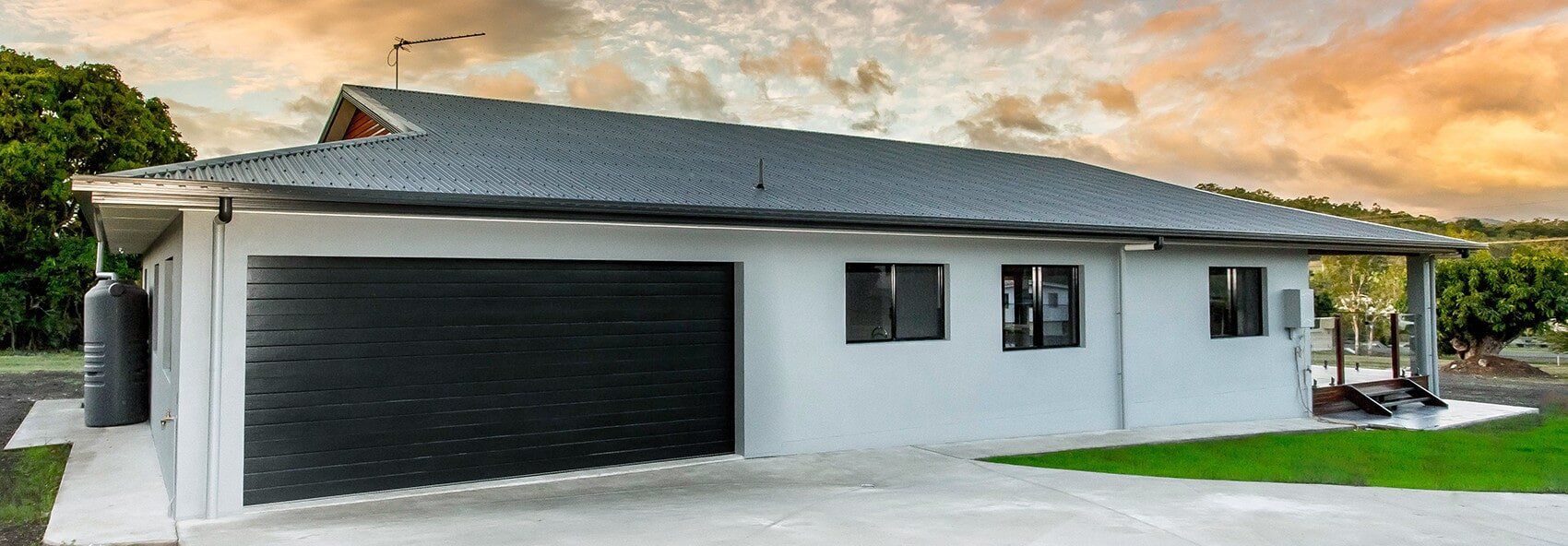 A white house with a black garage door and a gray roof