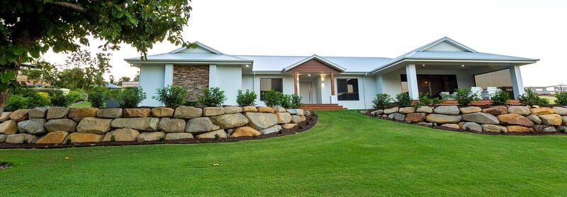 A large white house with a stone wall in front of it.