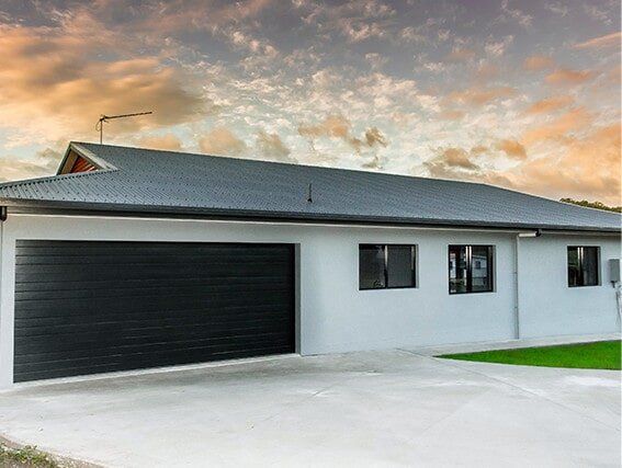 A white house with a black garage door and a gray roof.