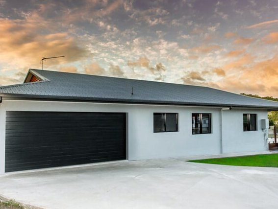 A white house with a black garage door and a gray roof.