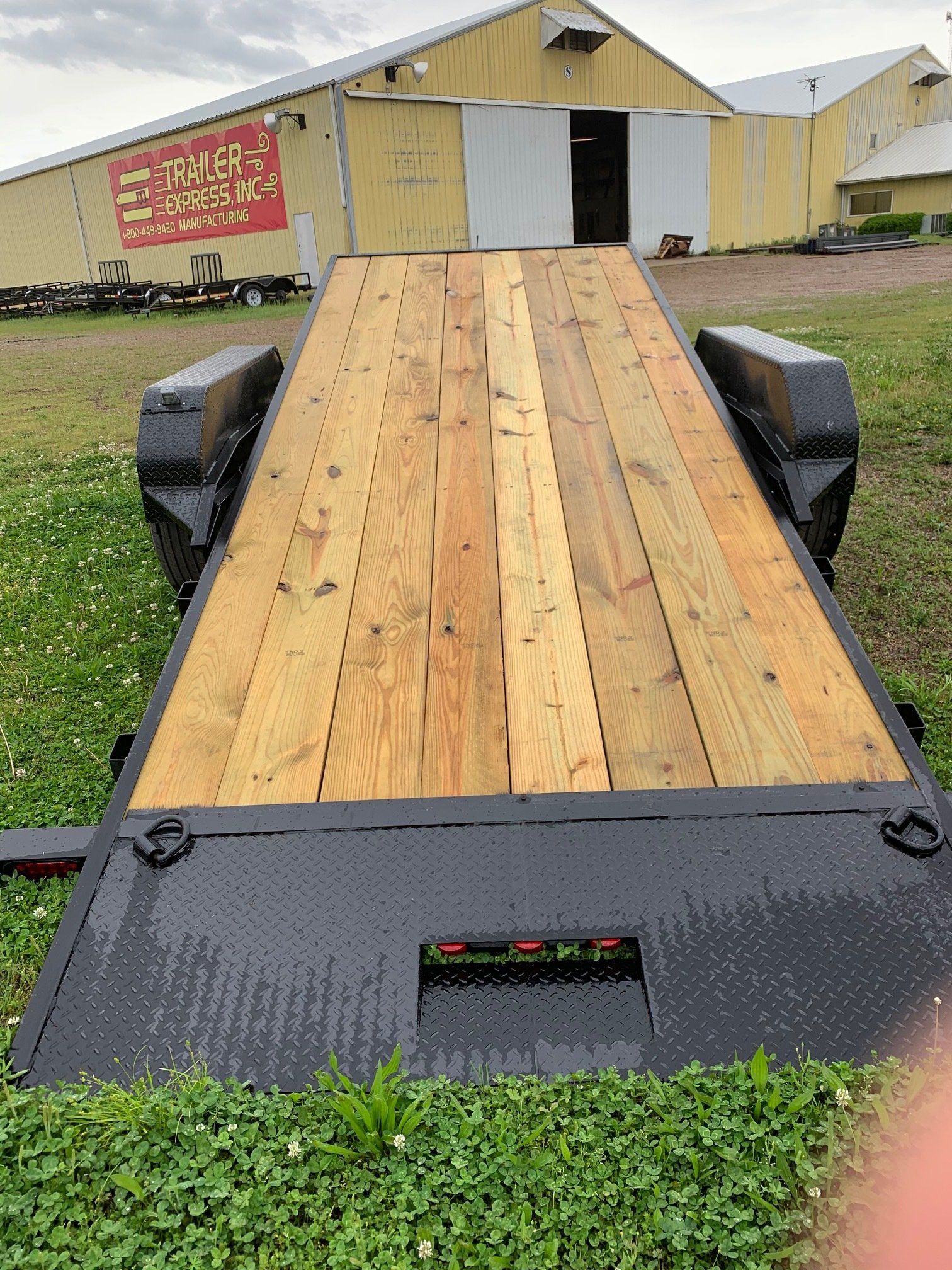 Wooden loading ramp leading to a yellow barn, with black side rails and a grassy foreground.