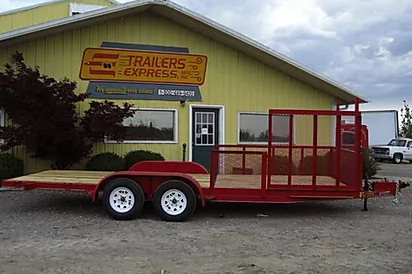 Red flatbed utility trailer with red mesh sides parked beside a yellow building.