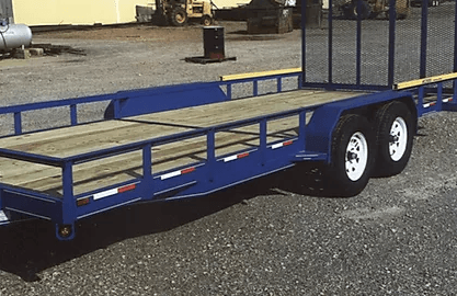 Blue flatbed utility trailer with dual axles and white wheels parked on gravel