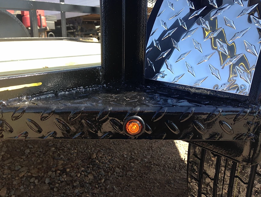 Black diamond-plate metal trailer frame with an orange marker light and a vented panel