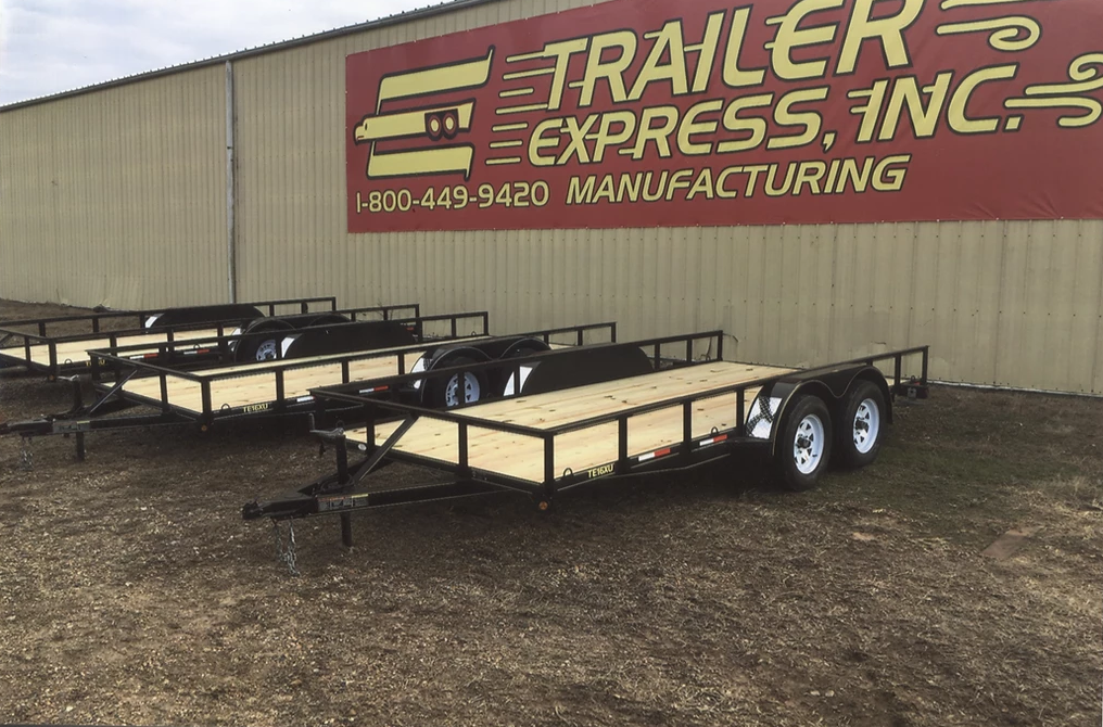 Trailer Express Inc. lot with two flatbed utility trailers parked in front of a building sign.