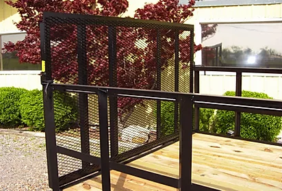 Black metal porch lift or railing beside a wooden deck with trees in the background